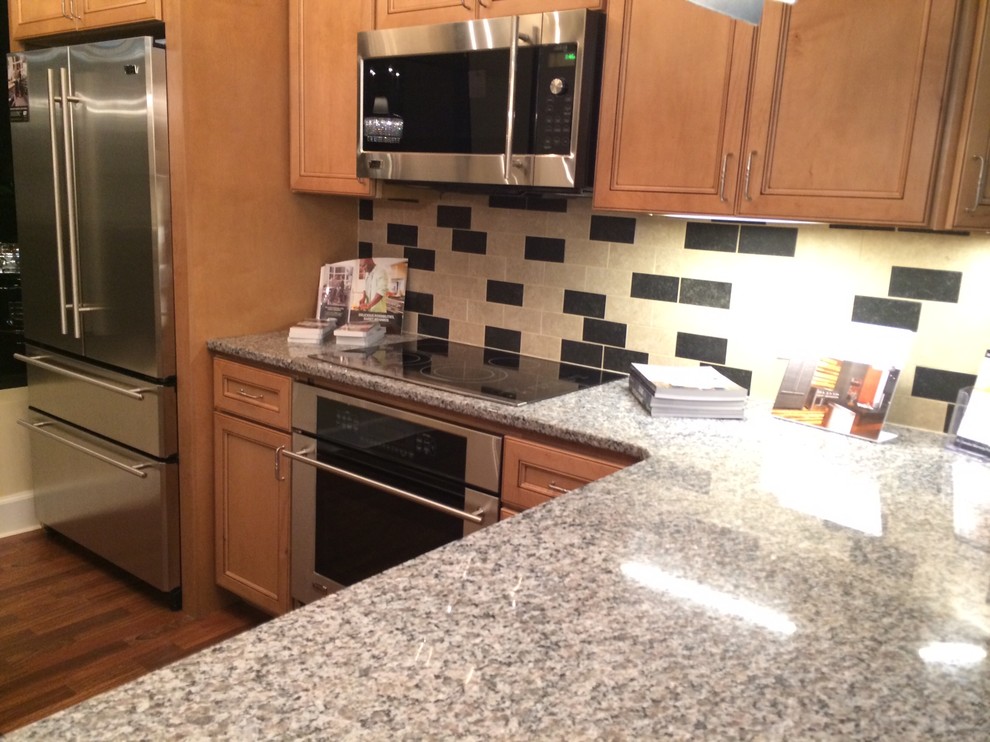 Mid-sized transitional l-shaped medium tone wood floor eat-in kitchen photo with recessed-panel cabinets, light wood cabinets, granite countertops, beige backsplash, porcelain backsplash, stainless steel appliances and a peninsula