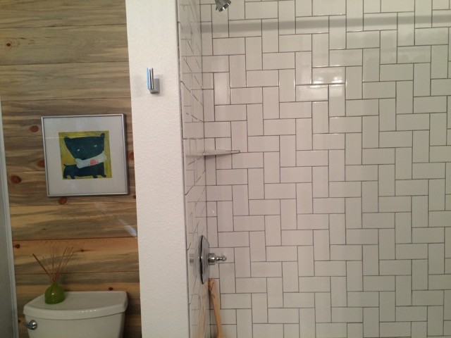 Photo of a mid-sized country 3/4 bathroom in Denver with shaker cabinets, white cabinets, an alcove tub, a shower/bathtub combo, white tile, ceramic tile, white walls and porcelain floors.