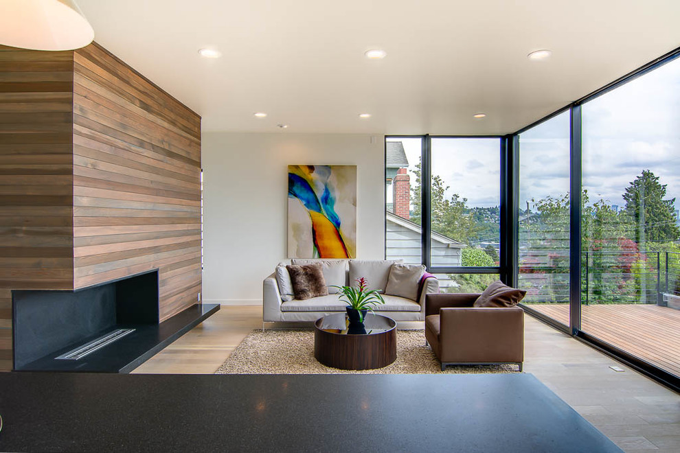 This is an example of a mid-sized modern formal open concept living room in Seattle with white walls, light hardwood floors, a corner fireplace, a stone fireplace surround and no tv.