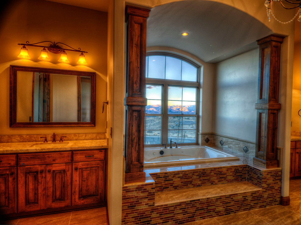 Photo of a large country master bathroom in Other with raised-panel cabinets, medium wood cabinets, a japanese tub, beige tile, brown tile, multi-coloured tile, matchstick tile, granite benchtops, brown walls, porcelain floors and an undermount sink.