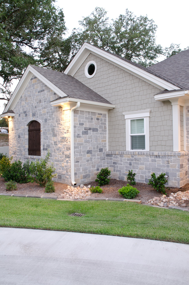 Photo of an expansive traditional two-storey blue exterior in Austin with stone veneer and a gable roof.