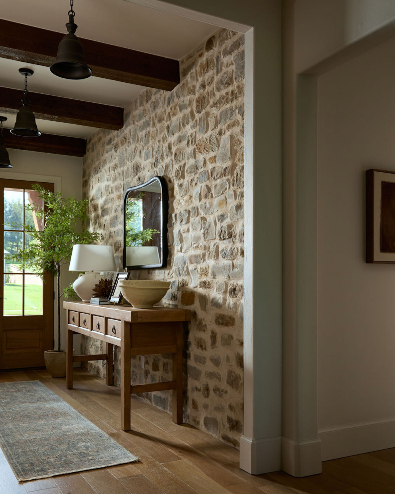 Farmhouse medium tone wood floor, brown floor and exposed beam foyer photo in Oklahoma City with beige walls and a dark wood front door