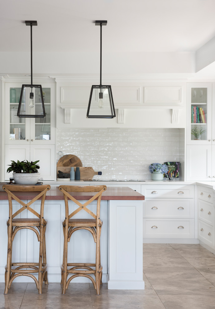 Large traditional l-shaped kitchen in Other with shaker cabinets, white cabinets, white splashback, with island, beige floor, white benchtop and subway tile splashback.