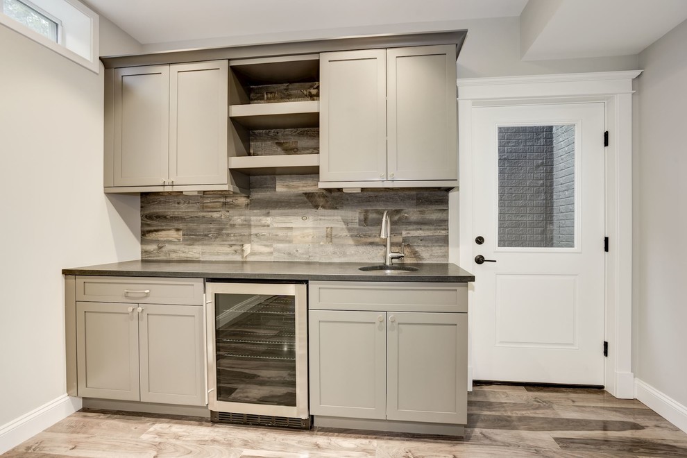 Inspiration for a small transitional single-wall wet bar in DC Metro with an undermount sink, shaker cabinets, grey cabinets, granite benchtops, multi-coloured splashback, timber splashback, laminate floors, multi-coloured floor and black benchtop.