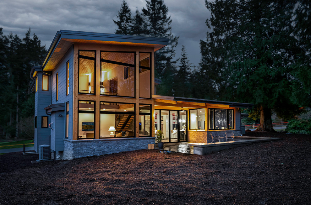 На фото: двухэтажный, серый дом среднего размера в современном стиле с облицовкой из камня, односкатной крышей, металлической крышей и отделкой планкеном