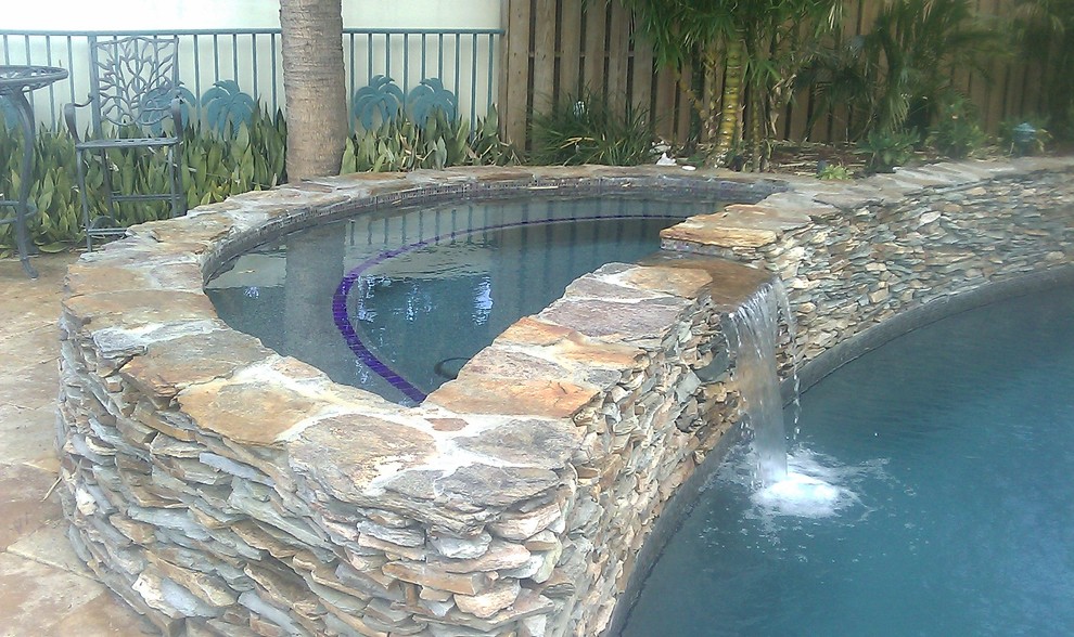 Inspiration for a mid-sized mediterranean backyard round pool in Miami with a hot tub and natural stone pavers.
