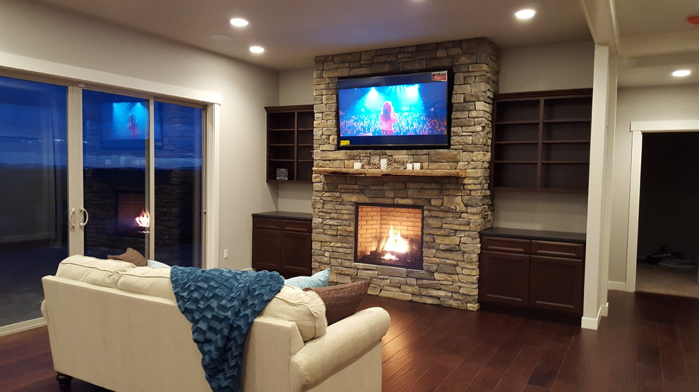Arts and crafts open concept family room in Seattle with grey walls, dark hardwood floors, a standard fireplace, a stone fireplace surround and a wall-mounted tv.