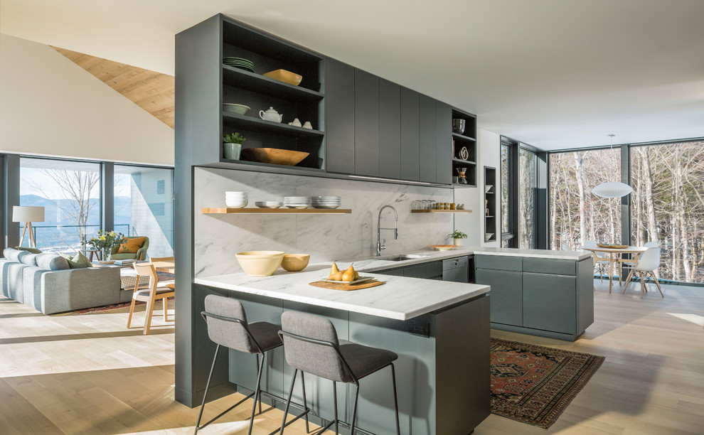 This is an example of a contemporary u-shaped eat-in kitchen in Burlington with an undermount sink, flat-panel cabinets, grey cabinets, white splashback, stainless steel appliances, light hardwood floors, a peninsula, beige floor and white benchtop.