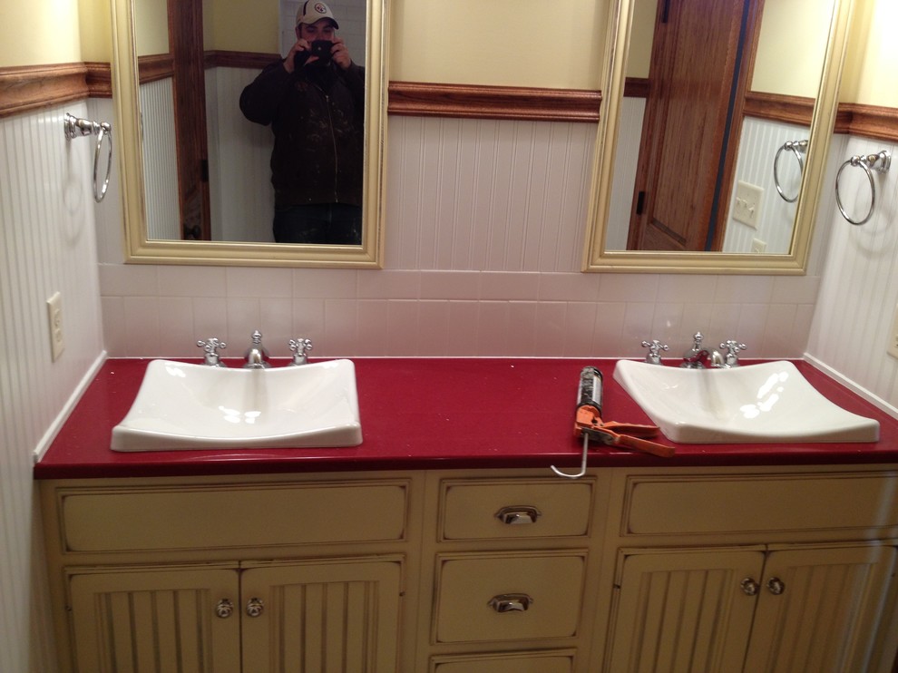 Mid-sized white tile and ceramic tile bathroom photo with a drop-in sink, distressed cabinets, solid surface countertops and beige walls