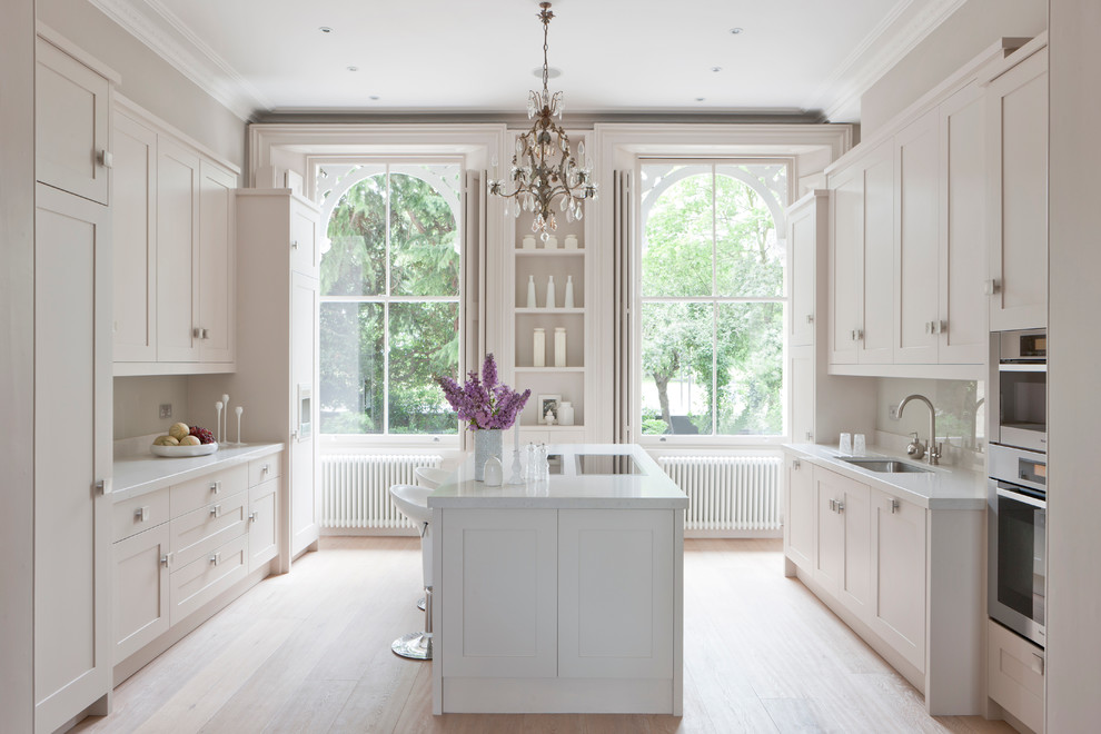 Inspiration for a transitional kitchen in London with recessed-panel cabinets, white cabinets, white splashback, glass sheet splashback and panelled appliances.