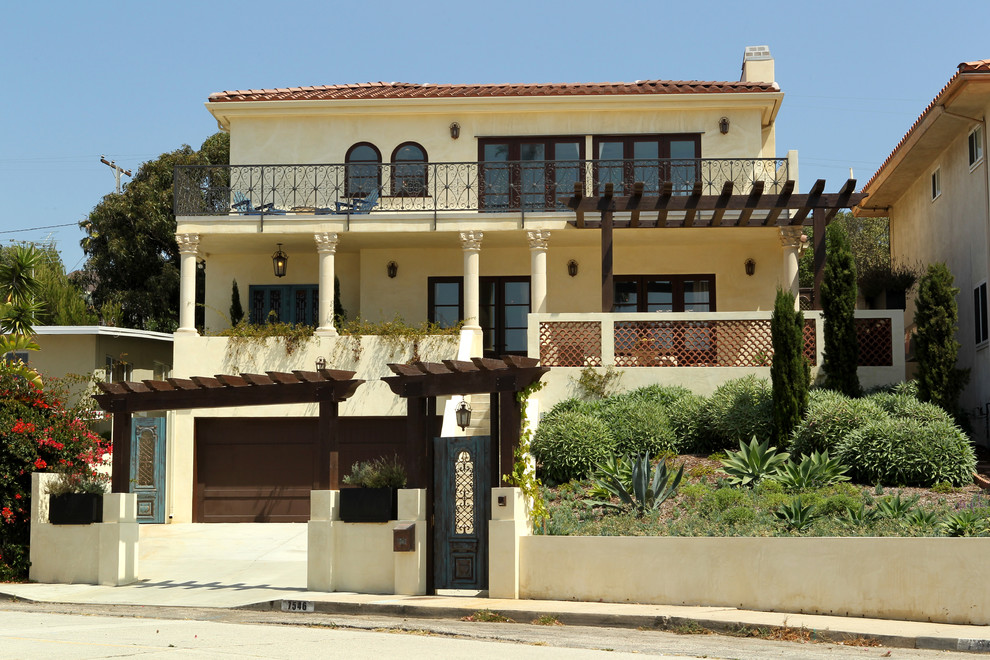 Photo of a large mediterranean two-storey stucco beige house exterior in Los Angeles with a hip roof and a tile roof.
