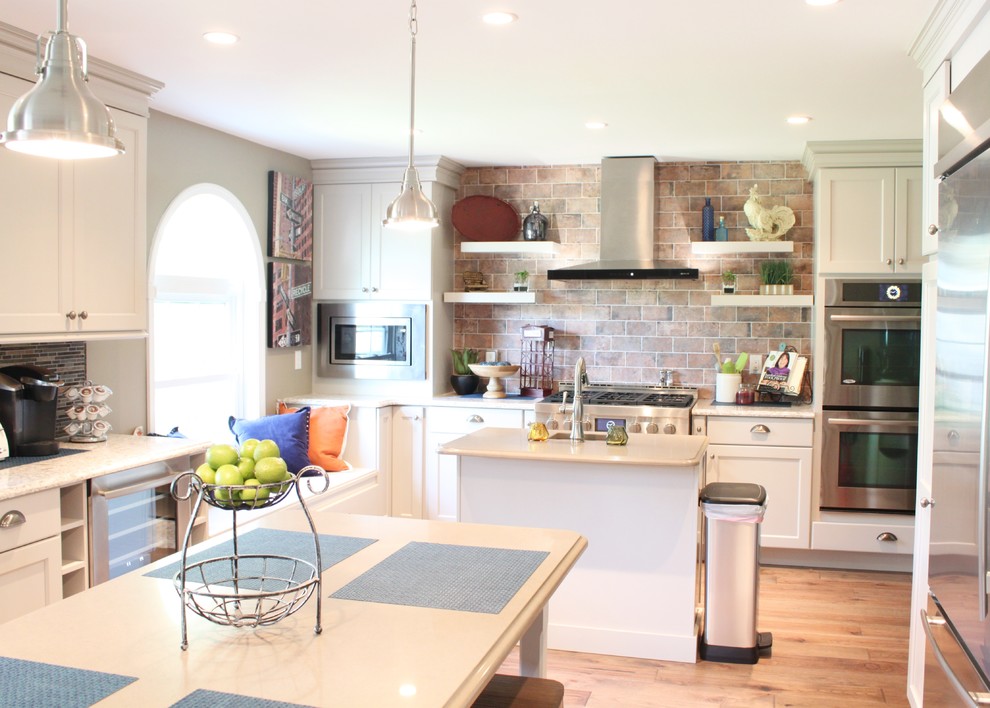 Large transitional u-shaped medium tone wood floor kitchen photo in Philadelphia with a double-bowl sink, shaker cabinets, white cabinets, quartz countertops, brown backsplash, mosaic tile backsplash, stainless steel appliances and two islands