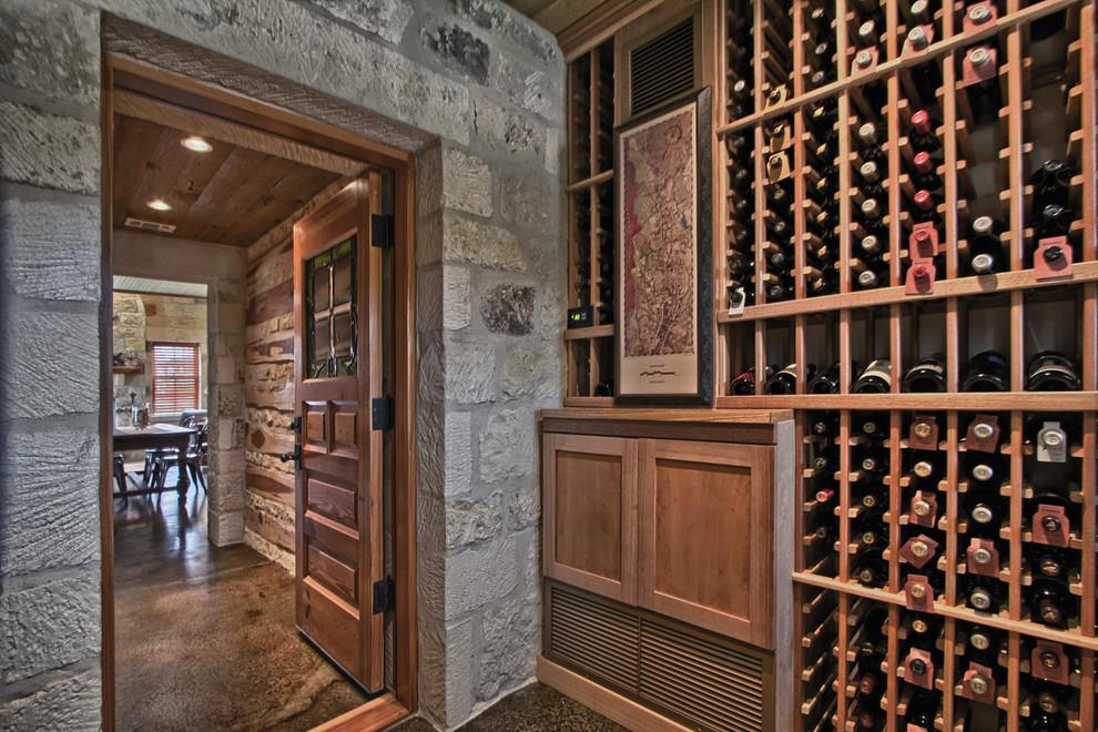 Inspiration for a mid-sized country wine cellar in Austin with storage racks, concrete floors and brown floor.