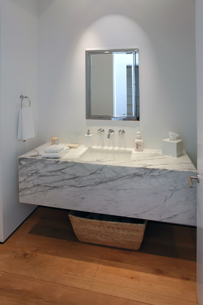 Photo of a mid-sized modern 3/4 bathroom in Miami with an undermount sink, marble benchtops, white tile, stone slab, flat-panel cabinets, white cabinets, white walls and medium hardwood floors.