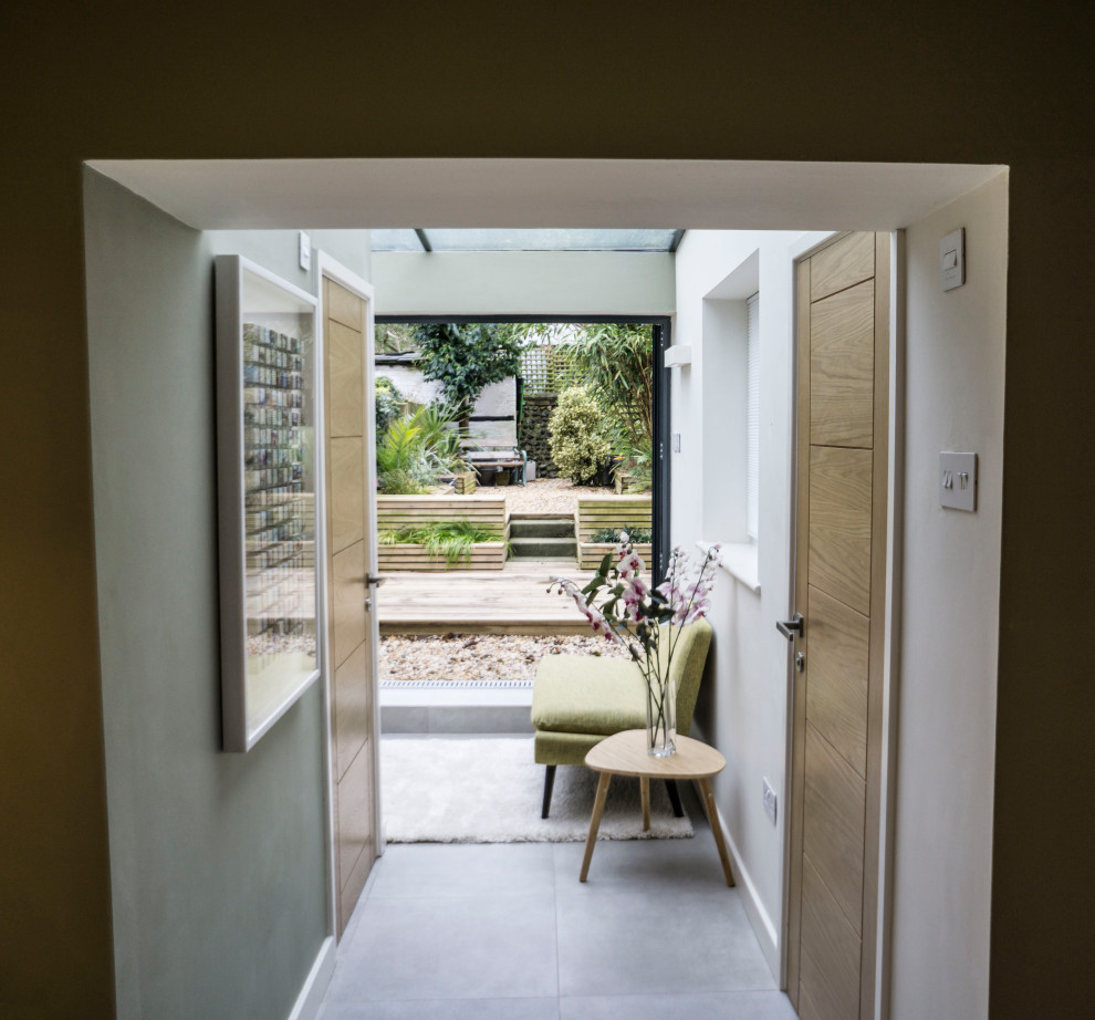 Photo of a small scandinavian sunroom in Kent with porcelain floors, a glass ceiling and grey floor.