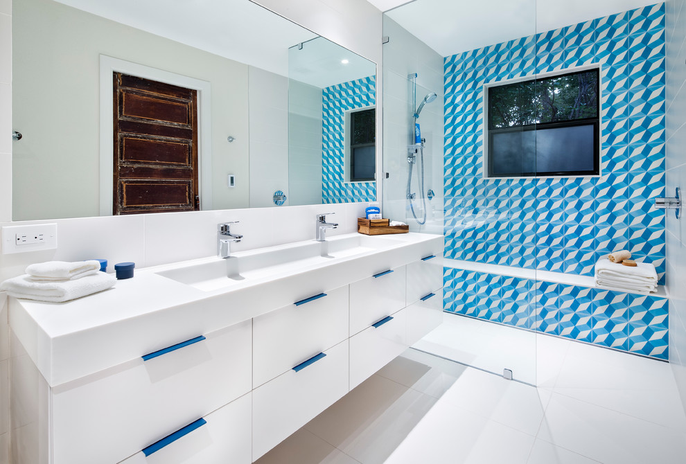 This is an example of a contemporary bathroom in Austin with flat-panel cabinets, white cabinets, a curbless shower, blue tile, white tile, white walls, a trough sink and an open shower.