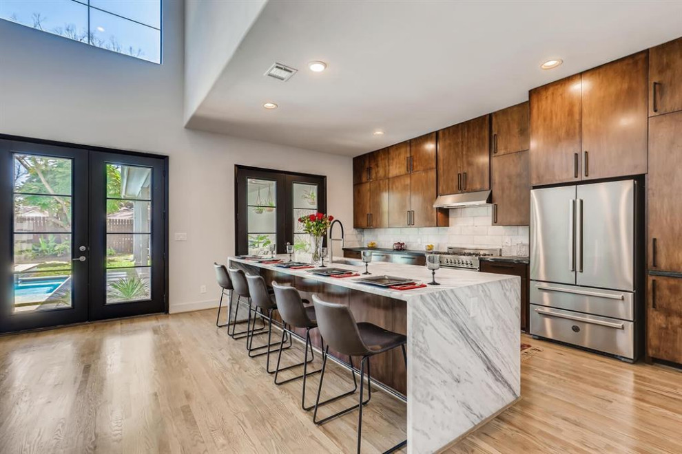 Large transitional single-wall eat-in kitchen in Houston with a farmhouse sink, raised-panel cabinets, brown cabinets, quartzite benchtops, beige splashback, ceramic splashback, stainless steel appliances, plywood floors, with island, beige floor, black benchtop and coffered.