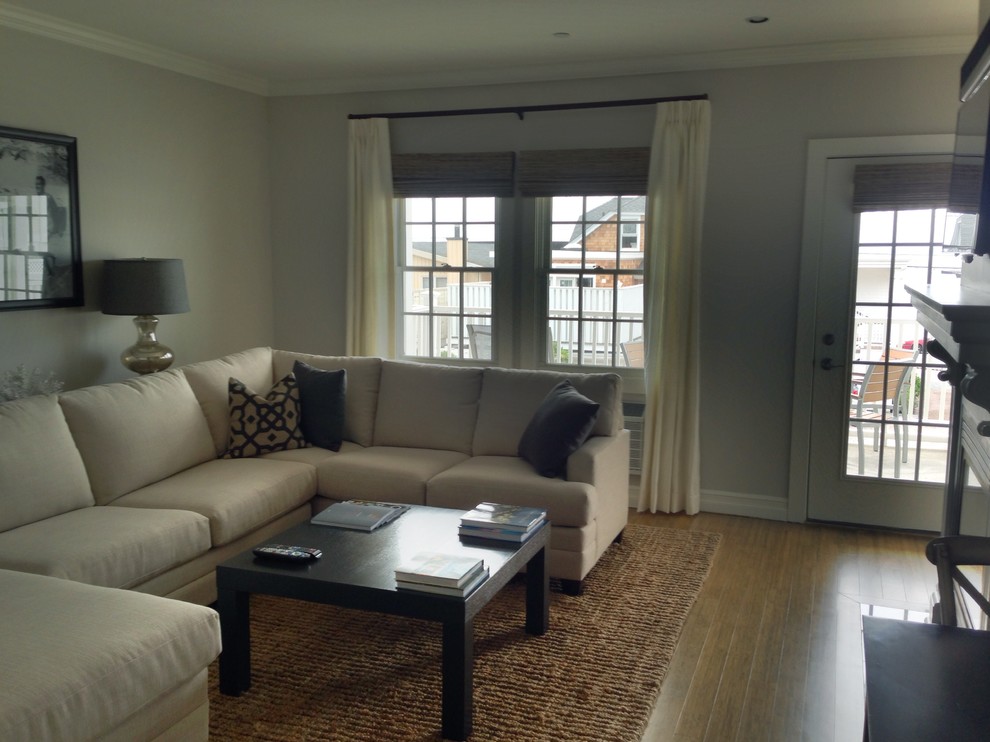 Small transitional enclosed family room in Providence with grey walls, light hardwood floors, a standard fireplace, a metal fireplace surround, a wall-mounted tv and brown floor.