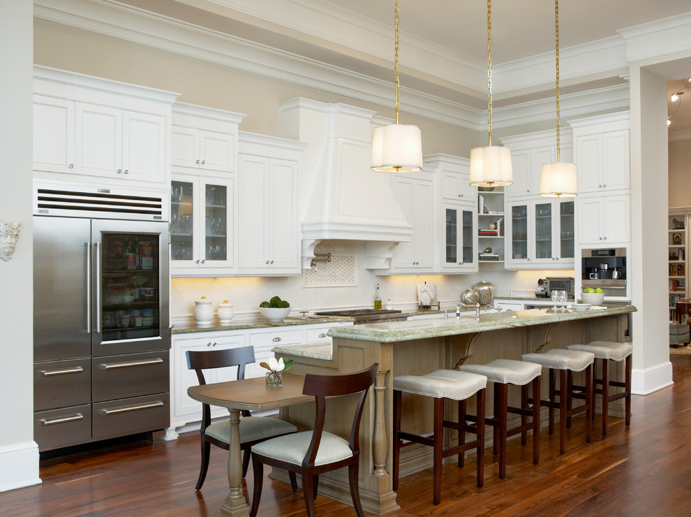 This is an example of a large traditional l-shaped separate kitchen in Other with recessed-panel cabinets, white cabinets, with island, granite benchtops, white splashback, stone tile splashback, stainless steel appliances, a farmhouse sink, dark hardwood floors and green benchtop.