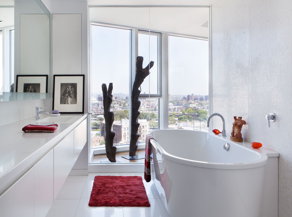 This is an example of a contemporary bathroom in New York with an integrated sink, a freestanding tub, white tile and mosaic tile.