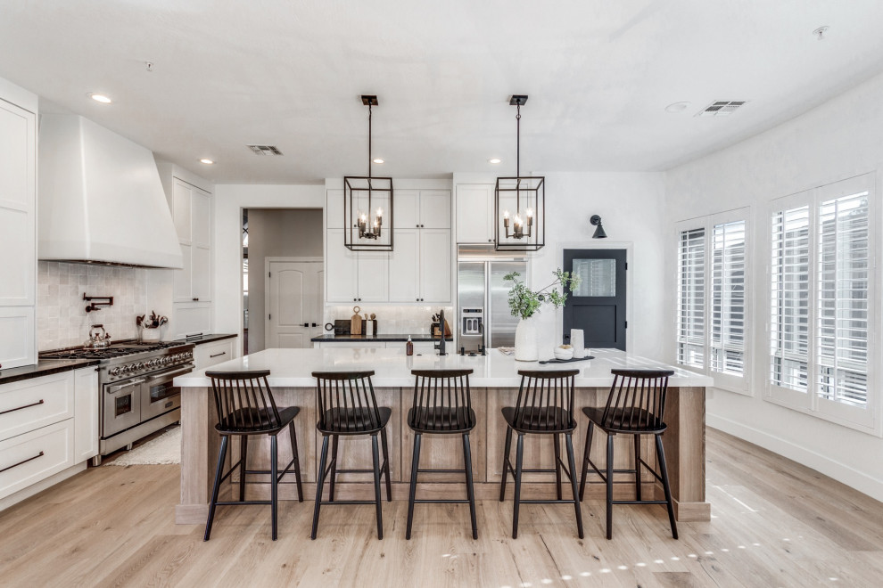 Inspiration for a large country l-shaped eat-in kitchen in Phoenix with a farmhouse sink, shaker cabinets, light wood cabinets, quartz benchtops, white splashback, terra-cotta splashback, stainless steel appliances, light hardwood floors, with island and white benchtop.