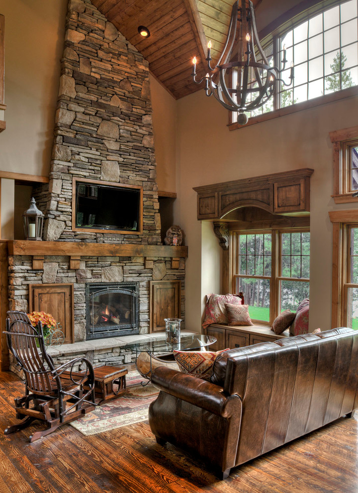 This is an example of a country formal open concept living room in Minneapolis with dark hardwood floors, a standard fireplace, a stone fireplace surround, beige walls and a wall-mounted tv.