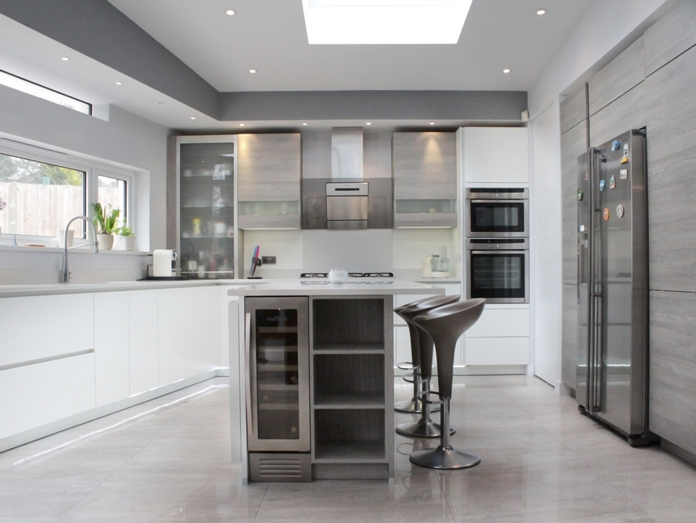This is an example of a mid-sized modern l-shaped eat-in kitchen in London with flat-panel cabinets, with island, an undermount sink, light wood cabinets, concrete benchtops, white splashback, porcelain splashback, stainless steel appliances and porcelain floors.