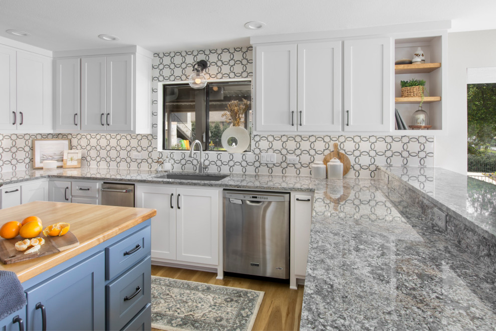 This is an example of a mid-sized transitional u-shaped eat-in kitchen in Dallas with an undermount sink, shaker cabinets, white cabinets, granite benchtops, grey splashback, mosaic tile splashback, stainless steel appliances, vinyl floors, a peninsula, brown floor and grey benchtop.