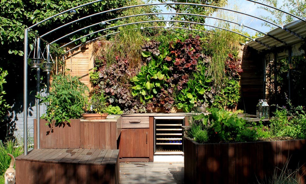 Design ideas for a large transitional backyard formal garden in London with a vertical garden and decking.