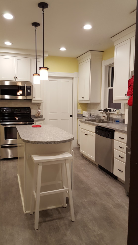Mid-sized transitional l-shaped vinyl floor enclosed kitchen photo with an undermount sink, shaker cabinets, white cabinets, solid surface countertops, multicolored backsplash, stone tile backsplash, stainless steel appliances and an island