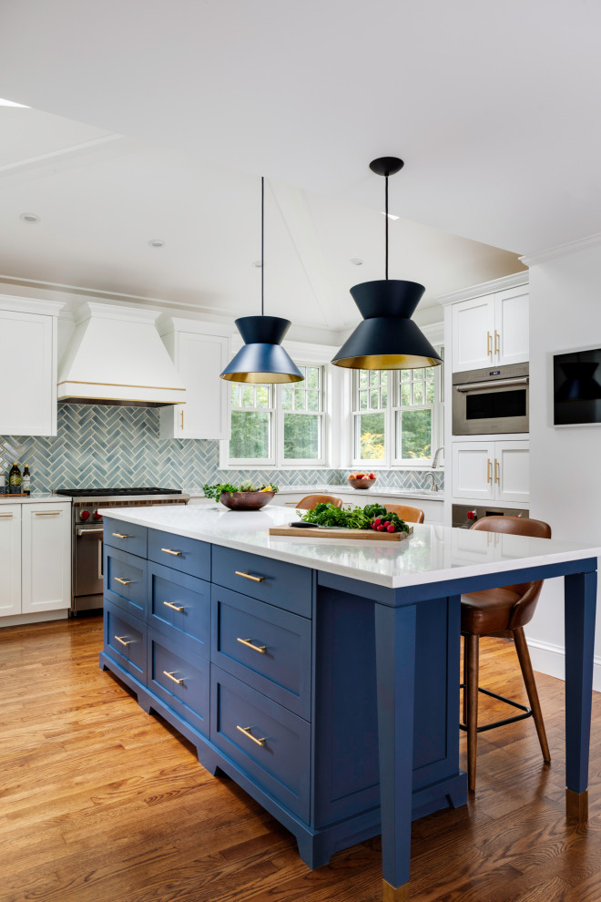 Inspiration for a mid-sized transitional u-shaped separate kitchen in Boston with white cabinets, quartzite benchtops, blue splashback, glass tile splashback, stainless steel appliances, medium hardwood floors, with island, vaulted, an undermount sink, shaker cabinets, brown floor and white benchtop.