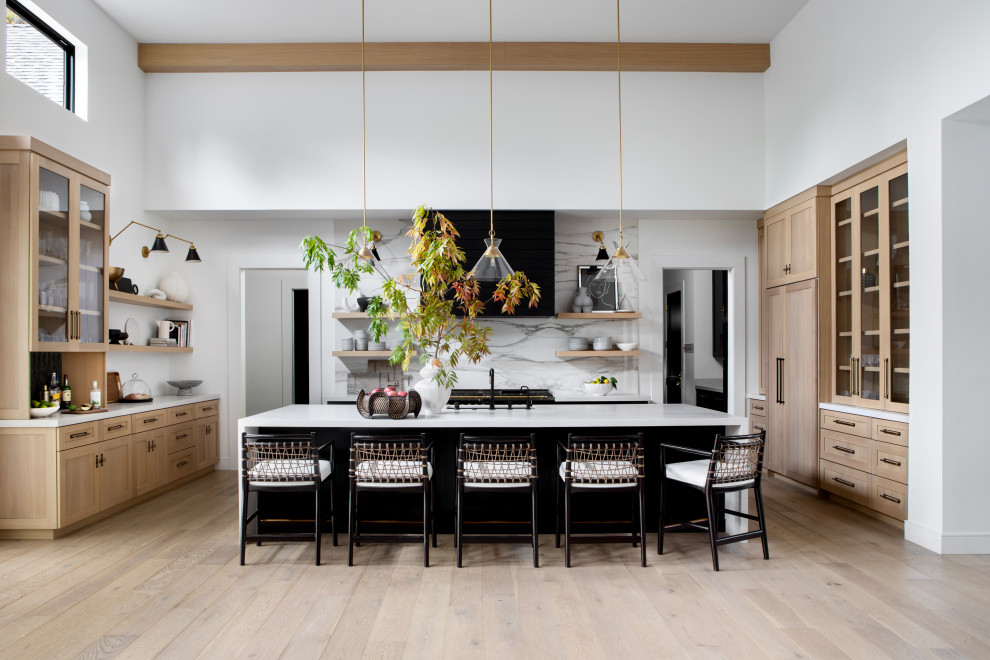 Design ideas for a transitional u-shaped kitchen in San Francisco with an undermount sink, shaker cabinets, light wood cabinets, white splashback, stone slab splashback, black appliances, light hardwood floors, with island, beige floor, white benchtop and exposed beam.