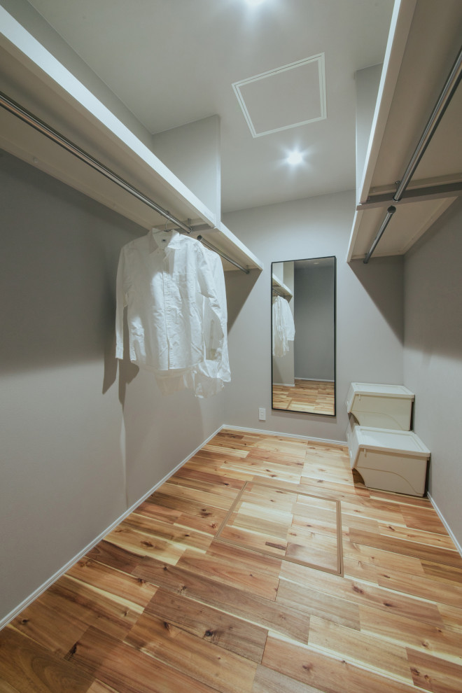 Imagen de armario y vestidor actual con suelo de madera en tonos medios, suelo beige y papel pintado