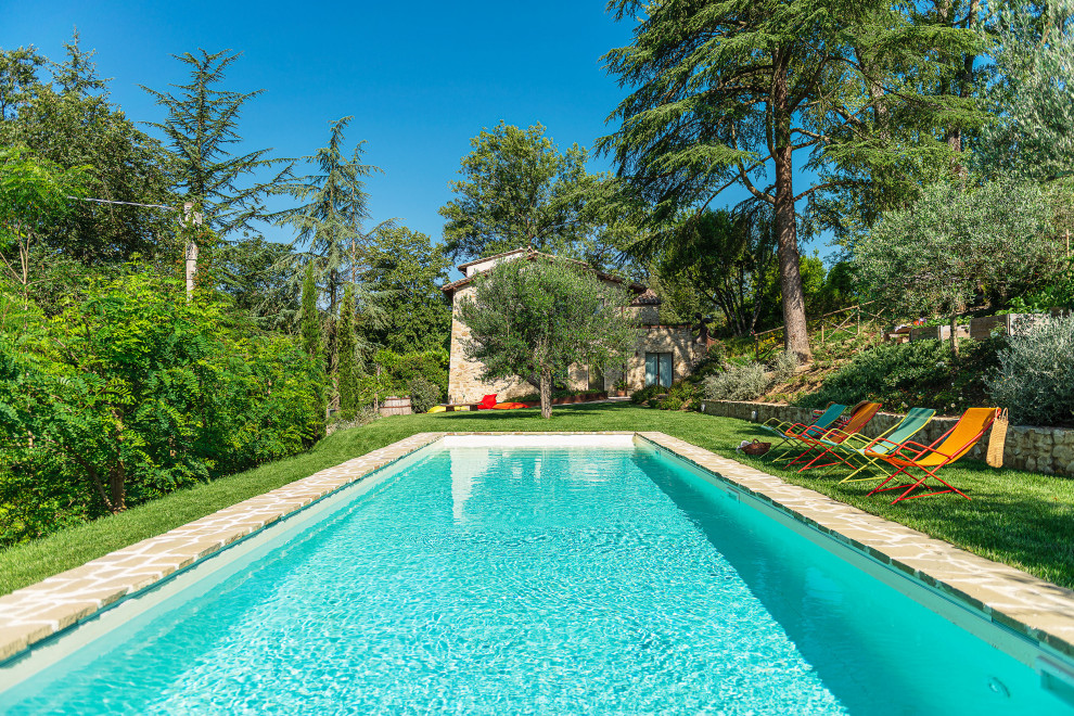 Ispirazione per una grande piscina mediterranea rettangolare davanti casa con una dépendance a bordo piscina e pavimentazioni in pietra naturale