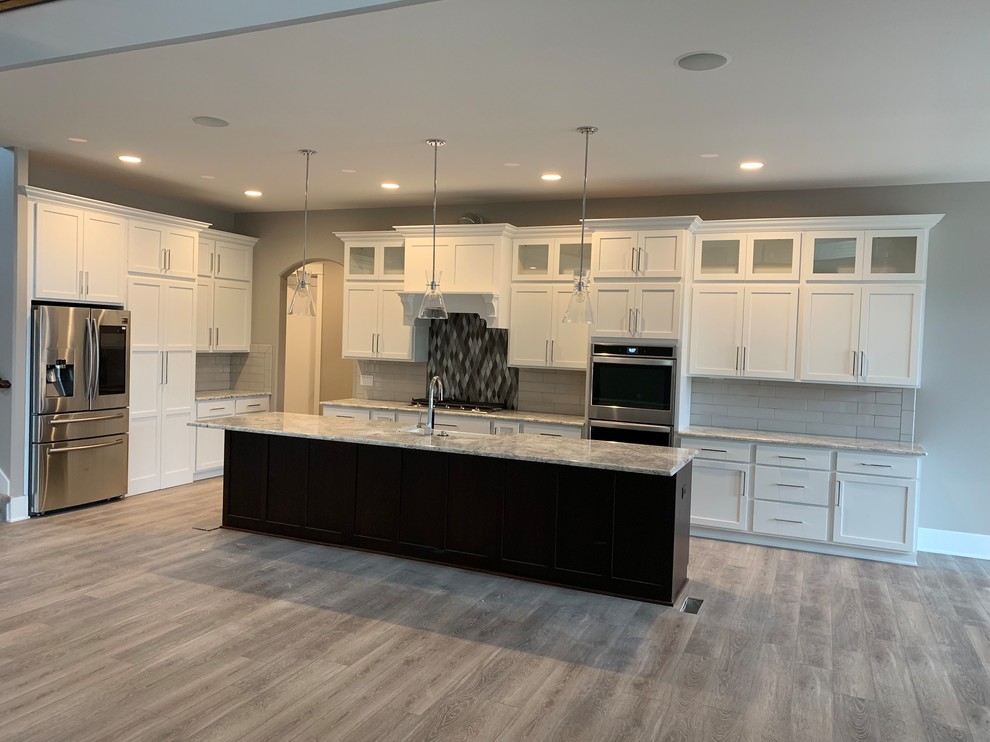 This is an example of a traditional kitchen in Omaha with shaker cabinets, white cabinets, with island, grey splashback and stainless steel appliances.