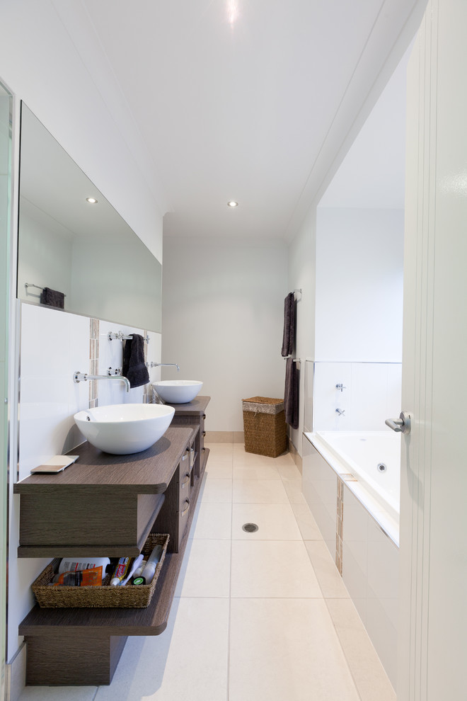 Photo of a contemporary bathroom in Cairns with a vessel sink, medium wood cabinets, wood benchtops, an alcove tub, white walls and ceramic floors.
