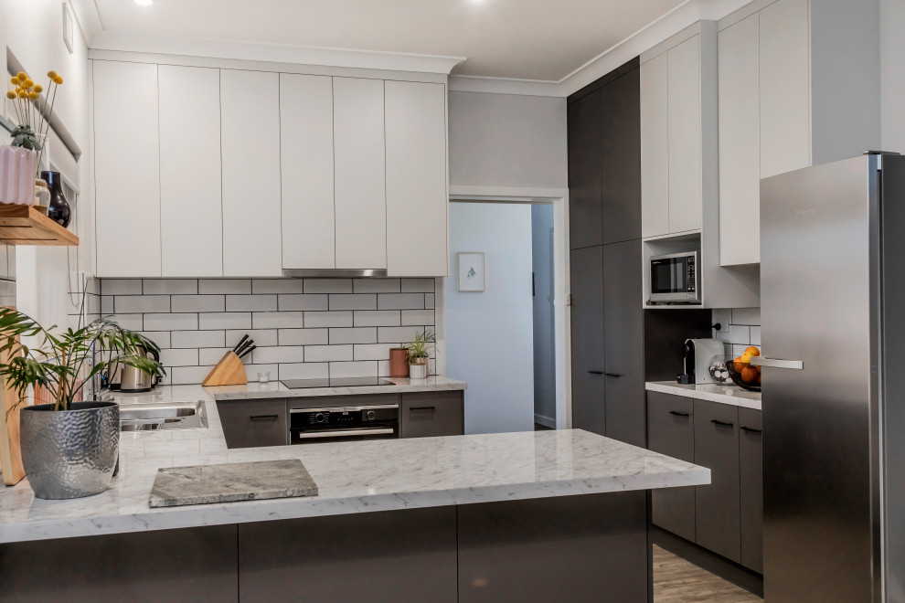 Mid-sized modern u-shaped eat-in kitchen in Adelaide with a drop-in sink, grey cabinets, laminate benchtops, white splashback, subway tile splashback, stainless steel appliances, bamboo floors, brown floor and white benchtop.