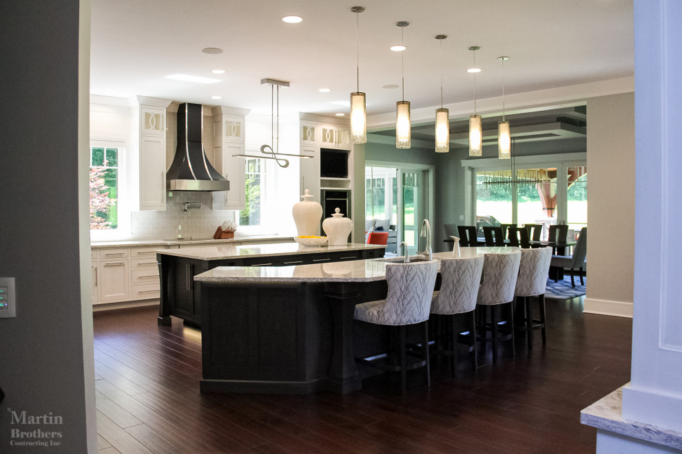 Example of a huge transitional l-shaped dark wood floor kitchen pantry design with an undermount sink, shaker cabinets, white cabinets, quartzite countertops, gray backsplash, ceramic backsplash, stainless steel appliances and two islands