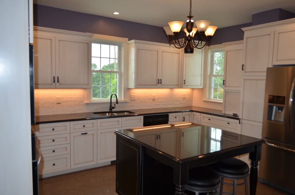 Eat-in kitchen - mid-sized transitional u-shaped brown floor eat-in kitchen idea with a double-bowl sink, recessed-panel cabinets, light wood cabinets, solid surface countertops, white backsplash, stone tile backsplash, stainless steel appliances and an island