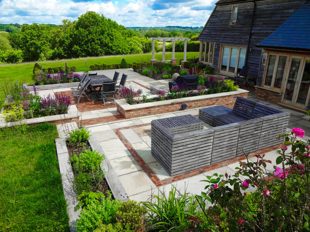 Design ideas for a large rural back full sun garden for summer in Sussex with natural stone paving.