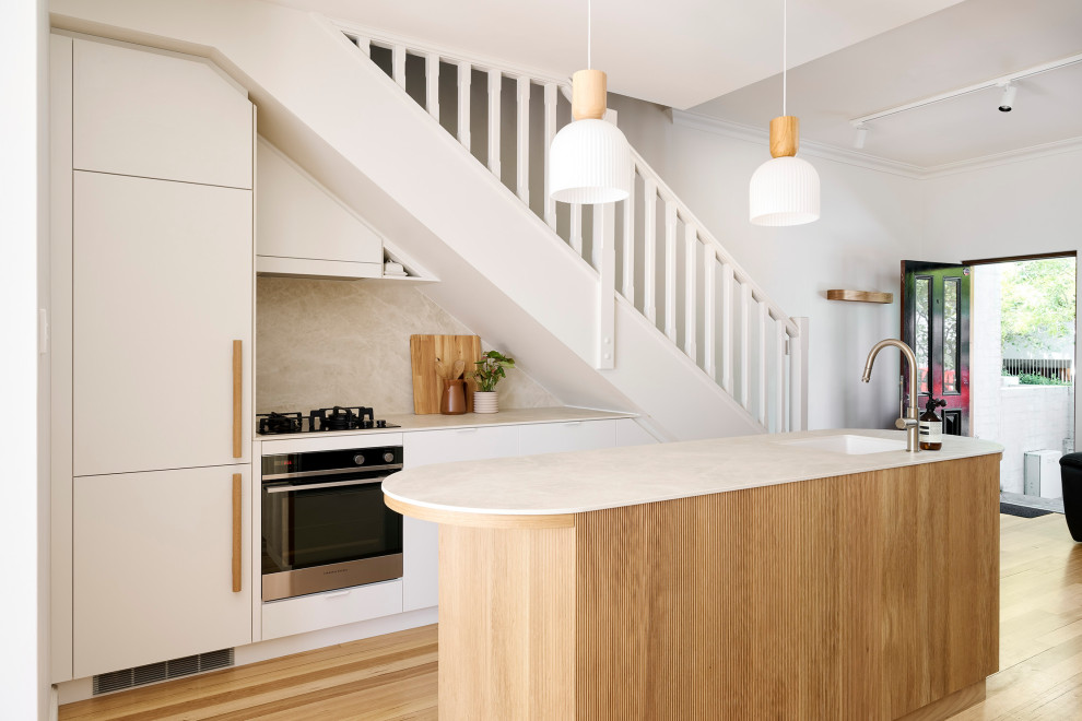 Inspiration for a small scandinavian galley eat-in kitchen in Perth with an undermount sink, flat-panel cabinets, white cabinets, quartz benchtops, beige splashback, porcelain splashback, black appliances, light hardwood floors, with island, brown floor, beige benchtop and vaulted.