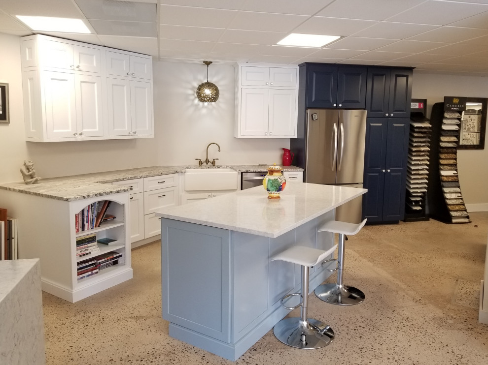 Mid-sized transitional single-wall eat-in kitchen in Denver with shaker cabinets, white cabinets, quartz benchtops, stainless steel appliances, concrete floors, with island, multi-coloured floor and grey benchtop.