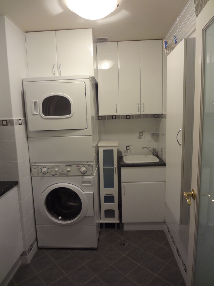 Photo of a mid-sized contemporary utility room in Perth with a drop-in sink, white cabinets, laminate benchtops, white walls, ceramic floors and a stacked washer and dryer.