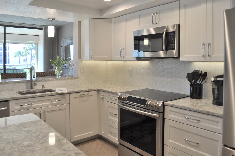 Example of a mid-sized transitional u-shaped eat-in kitchen design with an undermount sink, shaker cabinets, white cabinets, quartz countertops, white backsplash, marble backsplash, stainless steel appliances and no island