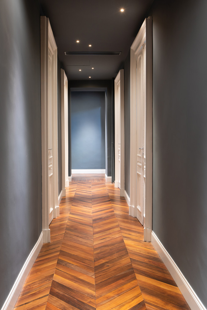 Modern hallway in Turin with blue walls and dark hardwood floors.
