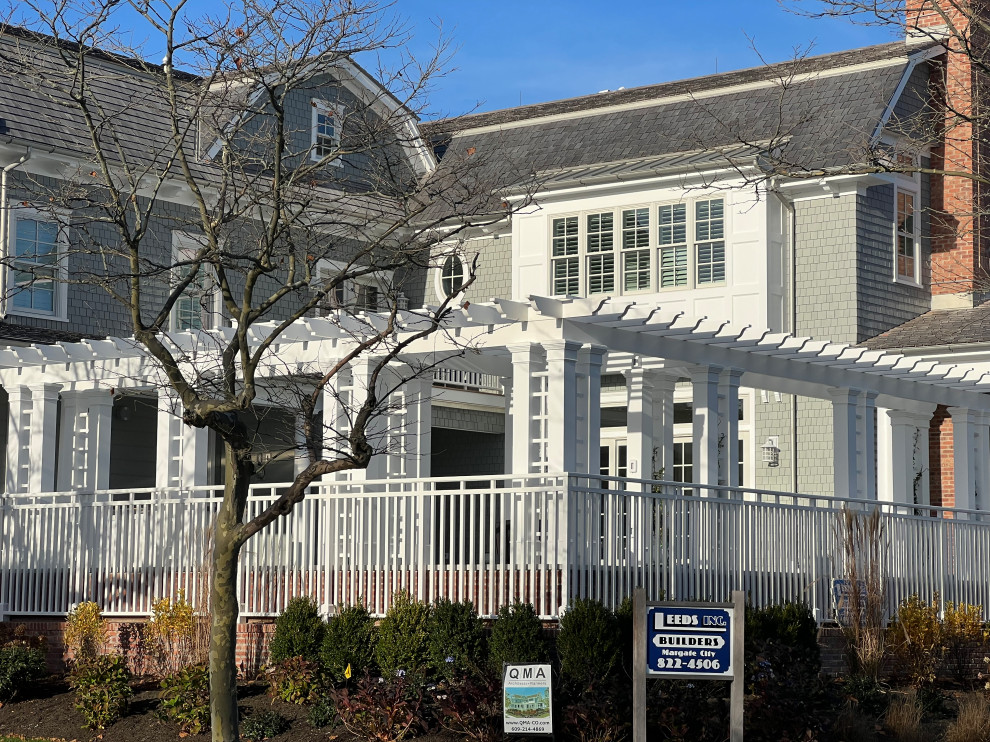 Large traditional three-storey grey house exterior in Philadelphia with wood siding, a gambrel roof, a shingle roof, a grey roof and shingle siding.