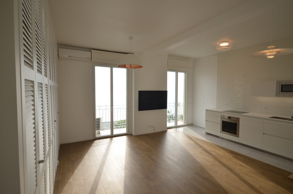 Bild på ett mellanstort funkis vardagsrum, med vita väggar, ljust trägolv, en väggmonterad TV och beiget golv