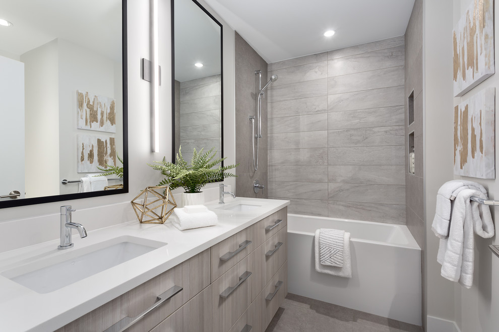 This is an example of a mid-sized contemporary 3/4 bathroom in Vancouver with flat-panel cabinets, an alcove tub, a shower/bathtub combo, gray tile, an undermount sink, grey floor, white benchtops, light wood cabinets, porcelain tile, beige walls, porcelain floors, solid surface benchtops and a shower curtain.