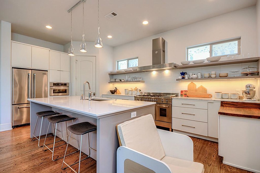Example of a transitional l-shaped medium tone wood floor open concept kitchen design in Houston with a double-bowl sink, shaker cabinets, white cabinets, marble countertops, white backsplash, marble backsplash, stainless steel appliances, an island and white countertops