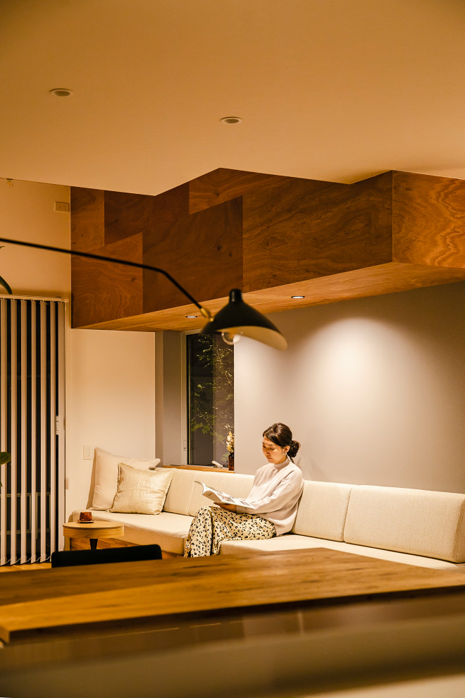 Example of a trendy open concept light wood floor and exposed beam living room design in Other with gray walls and no fireplace